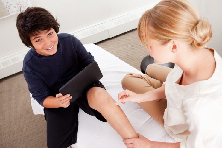 Young,Male,Receiving,Pediatric,Acupuncture,While,Playing,Games,On,A
