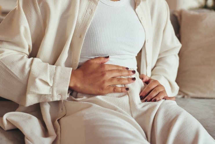 Woman,,Hands,And,Stomach,Pain,Of,Menstruation,On,Sofa,With